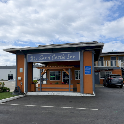 A modern storefront with a wooden entrance, glass doors, and a small sign; blue sky with clouds above.