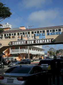 A busy seaside street with pastel buildings, parked cars, and a bright blue sky. Top it at 140 characters, always ending the sentence.