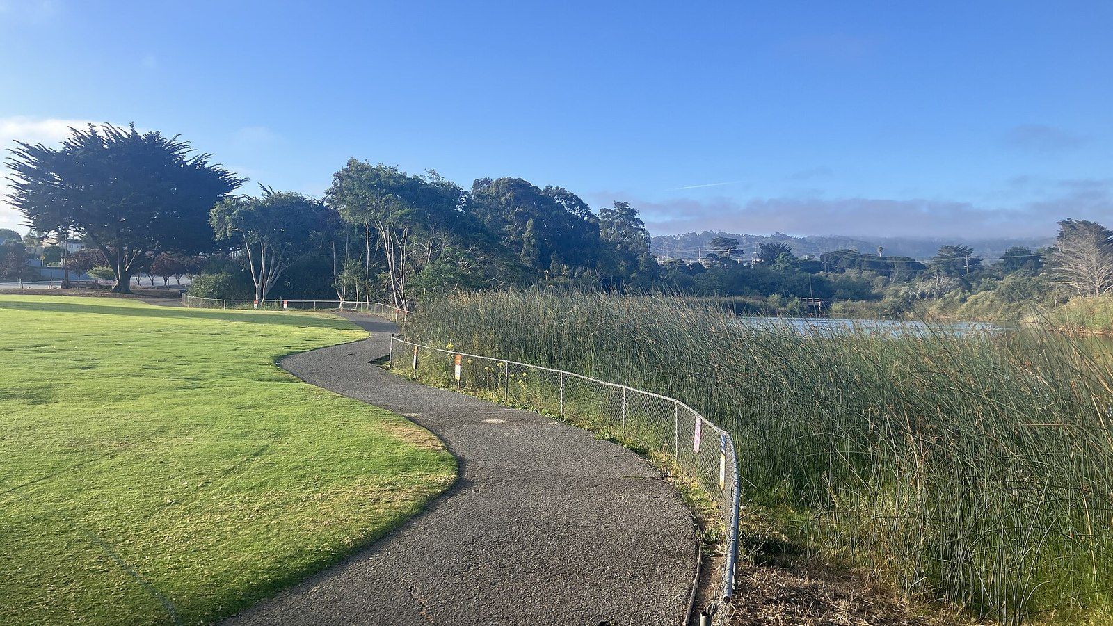 A paved path and lawn beside the lake at Laguna Grande Park in Seaside