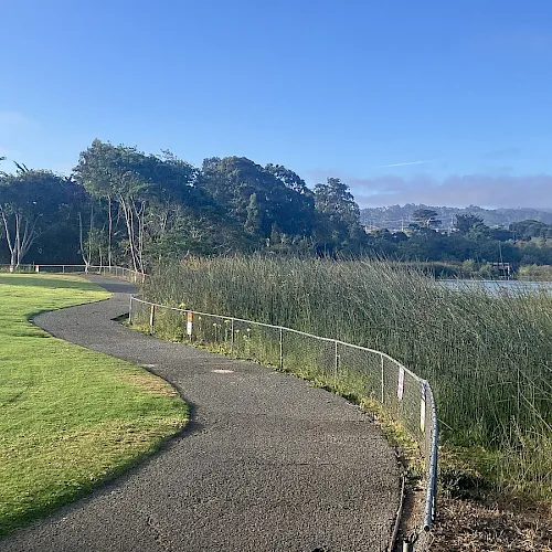 A paved path and lawn beside the lake at Laguna Grande Park in Seaside